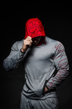 Stüdyoda kapüşonlu karanlık bir arka plana karşı duran sportif bir adam. Spor, güzellik