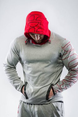 Stüdyoda beyaz bir arka planda kapüşonlu bir sporcu duruyor. Spor, güzellik