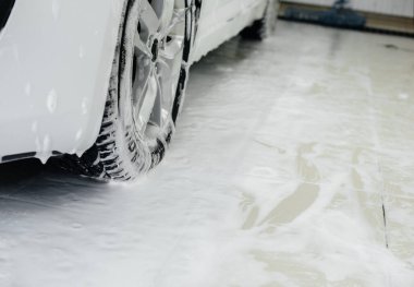 Köpüklü modern yıkama ve beyaz bir arabanın yüksek basınçlı suyu. Araba yıkama