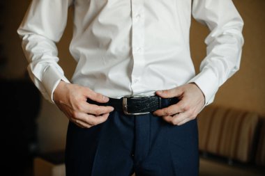 Şık bir adam yakın plan deri kemer takıyor. Moda.