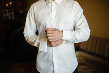 Şık genç adam kol düğmelerinin düğmelerini ilikliyor. Biçim