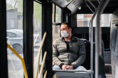 Genç maskeli bir adam salgın sırasında toplu taşıma araçlarını tek başına kullanıyor. Koruma ve önleme bölmesi 19