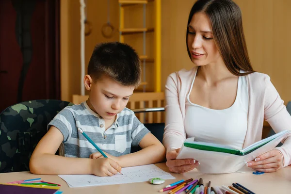 Genç bir anne evde oğluyla ev ödevi yapıyor. Ebeveynler ve eğitim