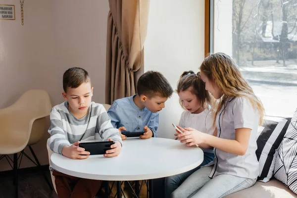 Çocuklar Bir Kafede Bir Masada Oturup Birlikte Cep Telefonu Oynarlar — Stok fotoğraf