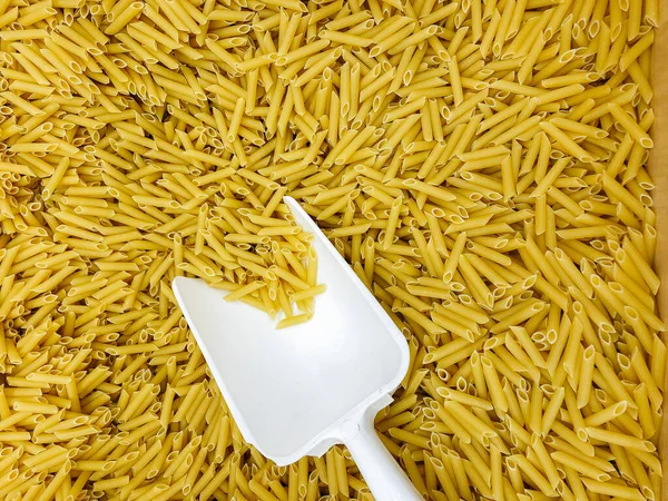 Large box of Italian pasta with a white scoop close-up. Food