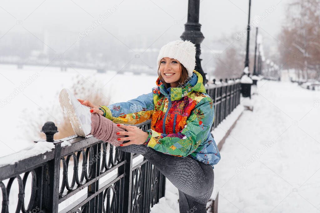 A young athletic girl is warming up before running on a frosty day. Fitness, running