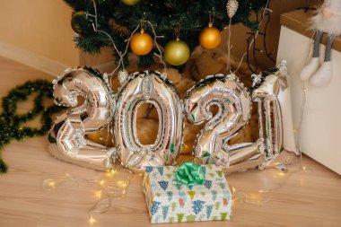 Sevimli gülümseyen bebek, Noel ağacının altında yatıyor ve hediyelerle oynuyor. Noel ve Yeni Yıl kutlamaları