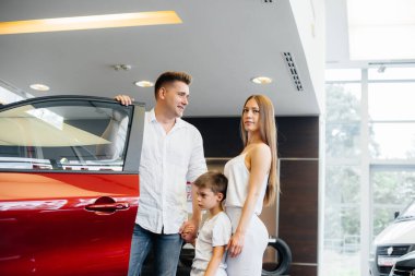 Mutlu genç bir aile araba galerisinden yeni bir araba seçer ve satın alır. Yeni bir araba alıyorum.