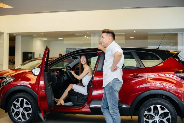 一对快乐的年轻夫妇在一家汽车经销店选择并购买了一辆新车 买一辆新车 — 图库照片