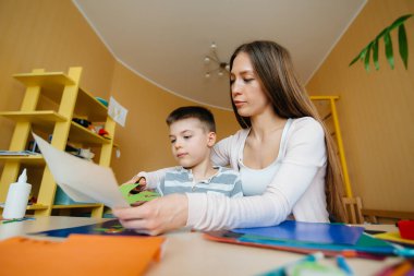 Genç bir anne evde oğluyla ev ödevi yapıyor. Ebeveynler ve eğitim