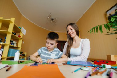 Genç bir anne evde oğluyla ev ödevi yapıyor. Ebeveynler ve eğitim