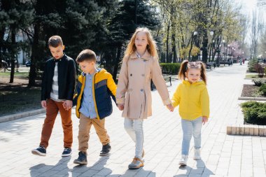 Bir grup çocuk birlikte oynuyor ve parkta el ele tutuşuyorlar. Arkadaşlar, çocuklar.