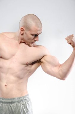 Beyaz arka planda üstsüz poz veren seksi bir sporcu. Fitness