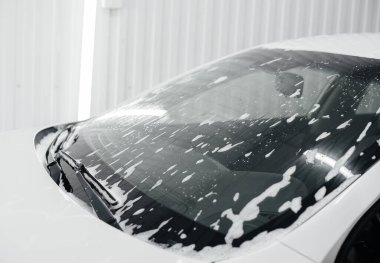 Köpüklü modern yıkama ve beyaz bir arabanın yüksek basınçlı suyu. Araba yıkama