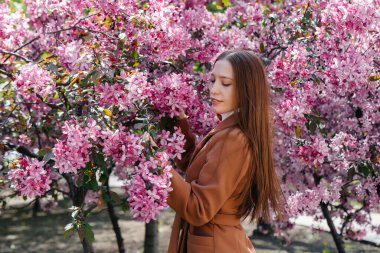 Güzel bir genç kız, bahar günü çiçek açan bir elma bahçesinde yürür. Yaşam tarzı, eğlence.