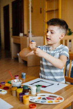 Odasında küçük sevimli bir çocuk oynuyor ve resim yapıyor. Eğlence ve eğlence. Evde kal.