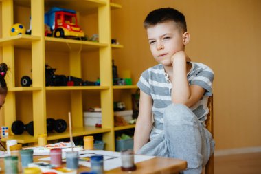 Odasında küçük sevimli bir çocuk oynuyor ve resim yapıyor. Eğlence ve eğlence. Evde kal.