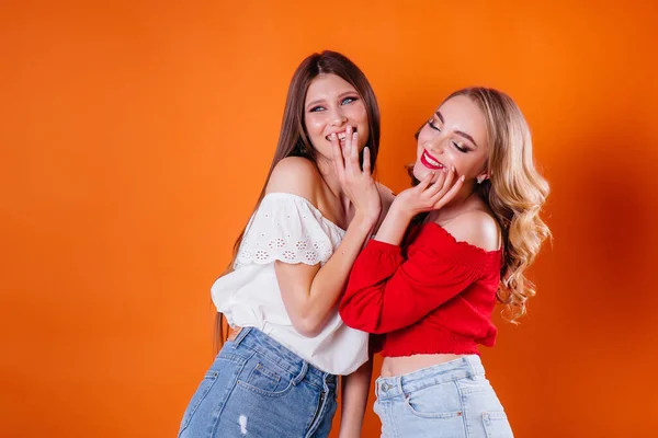 Duas Meninas Jovens Bonitas Mostram Emoções Sorrisos Estúdio Fundo Laranja — Fotografia de Stock