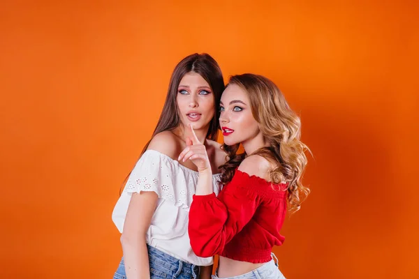 Duas Meninas Jovens Bonitas Mostram Emoções Sorrisos Estúdio Fundo Laranja — Fotografia de Stock