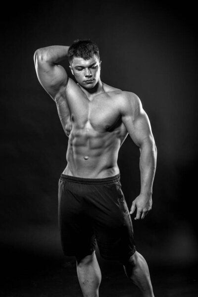 Sexy young athlete posing on a black background in the Studio. Fitness, bodybuilding, black and white
