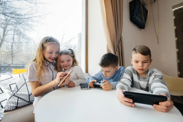 Crianças Sentam Uma Mesa Café Jogam Telefones Celulares Conjunto Entretenimento — Fotografia de Stock