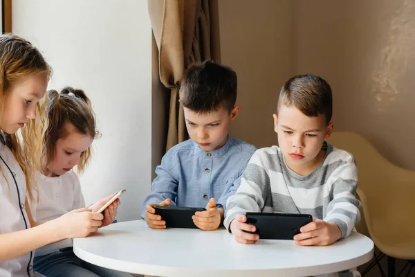 Dzieci Siedzą Przy Stole Kawiarni Bawią Się Razem Telefonami Komórkowymi — Zdjęcie stockowe