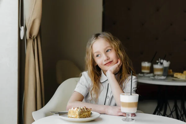 Uma Menina Bonita Está Sentada Café Olhando Para Bolo Cacau — Fotografia de Stock