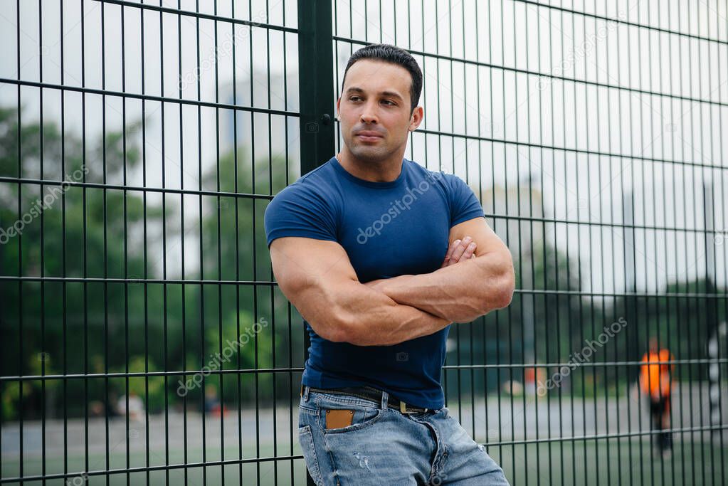 Sports guy stands near the sports field. Bodybuilding