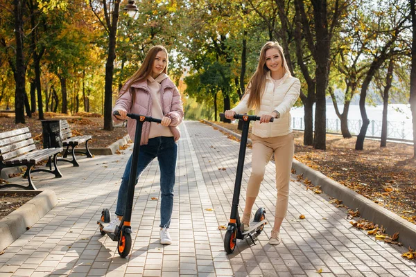 Két Fiatal Gyönyörű Lány Elektromos Robogózik Parkban Egy Meleg Őszi — Stock Fotó