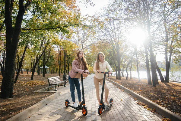 Két Fiatal Gyönyörű Lány Elektromos Robogózik Parkban Egy Meleg Őszi — Stock Fotó