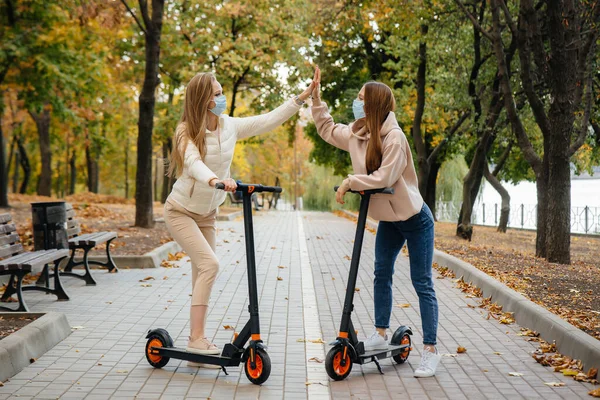 Két Fiatal Álarcos Gyönyörű Lány Robogózik Parkban Egy Meleg Őszi — Stock Fotó