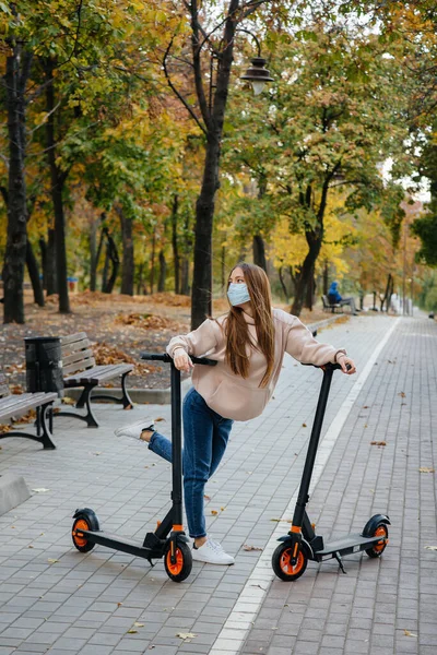 Egy Fiatal Gyönyörű Lány Maszkban Lovagol Parkban Egy Elektromos Robogón — Stock Fotó