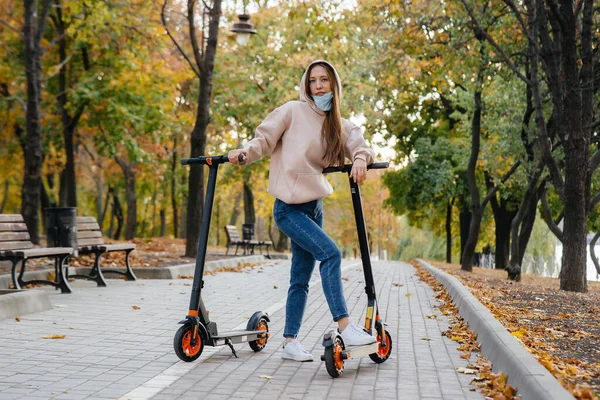 Egy Fiatal Gyönyörű Lány Maszkban Lovagol Parkban Egy Elektromos Robogón — Stock Fotó