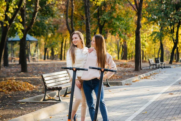 Duas Meninas Bonitas Jovens Montam Scooters Elétricos Parque Dia Quente — Fotografia de Stock