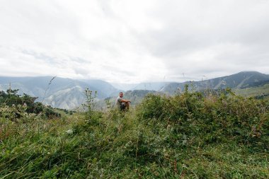 Genç bir adam oturur ve seyahat ederken güzel dağların çarpıcı manzarasının tadını çıkarır. Vahşi yaşam