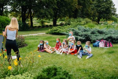 Maskeli bir okul çocuğu sınıfı salgın sırasında açık havada eğitim görüyor. Okula dönüyorum, salgın sırasında öğreniyorum.
