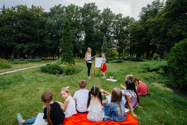 A teacher teaches a class of children in an outdoor Park. Back to school, learning during the pandemic