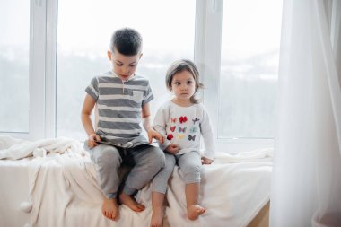 Erkek ve kız kardeş pencere kenarında oturuyorlar ve kitap okuyorlar. Mutluluk, aile