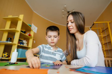 Genç bir anne evde oğluyla ev ödevi yapıyor. Ebeveynler ve eğitim