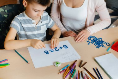 Genç bir anne evde oğluyla ev ödevi yapıyor. Ebeveynler ve eğitim