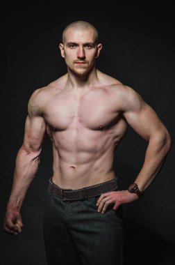 Sportif seksi adam karanlık bir zeminde üstsüz duruyor. Spor, güzellik
