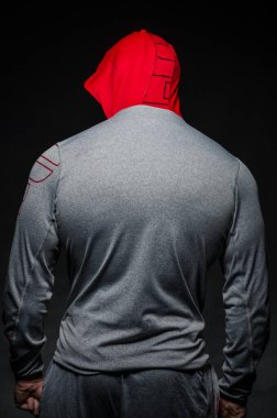 Stüdyoda kapüşonlu karanlık bir arka plana karşı duran sportif bir adam. Spor, güzellik