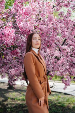 Güzel bir genç kız, bahar günü çiçek açan bir elma bahçesinde yürür. Yaşam tarzı, eğlence.