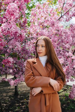 Güzel bir genç kız, bahar günü çiçek açan bir elma bahçesinde yürür. Yaşam tarzı, eğlence.