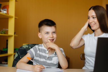 Bir anne ve çocuğu evde bilgisayarın önünde uzaktan öğrenme ile meşguller. Evde kal, çalış.