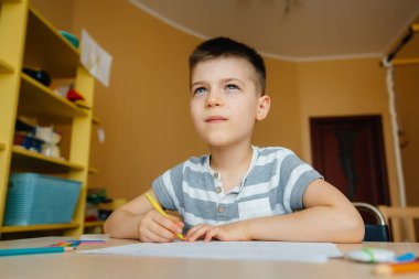 Okul çağındaki bir çocuk evde ödev yapar. Okulda eğitim.