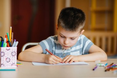 Okul çağındaki bir çocuk evde ödev yapar. Okulda eğitim.
