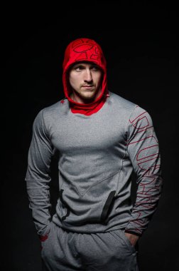 Stüdyoda kapüşonlu karanlık bir arka plana karşı duran sportif bir adam. Spor, güzellik