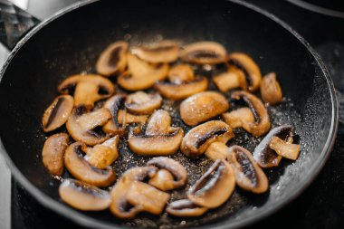 İnce dilimlenmiş taze çiğ mantarlar yakın plan çekimde kızartılır. Sağlıklı beslenme