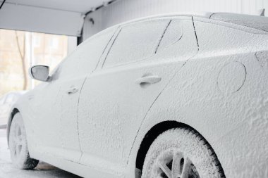 Köpüklü modern yıkama ve beyaz bir arabanın yüksek basınçlı suyu. Araba yıkama